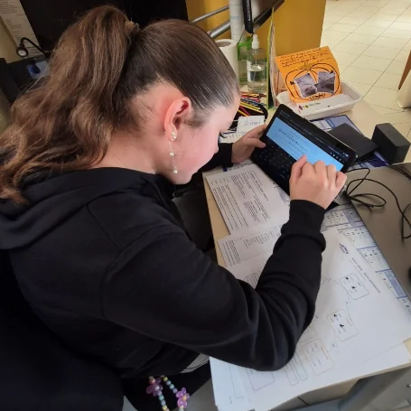 Saisie de l’histoire collective sur une tablette, avec le plan manuscrit à côté