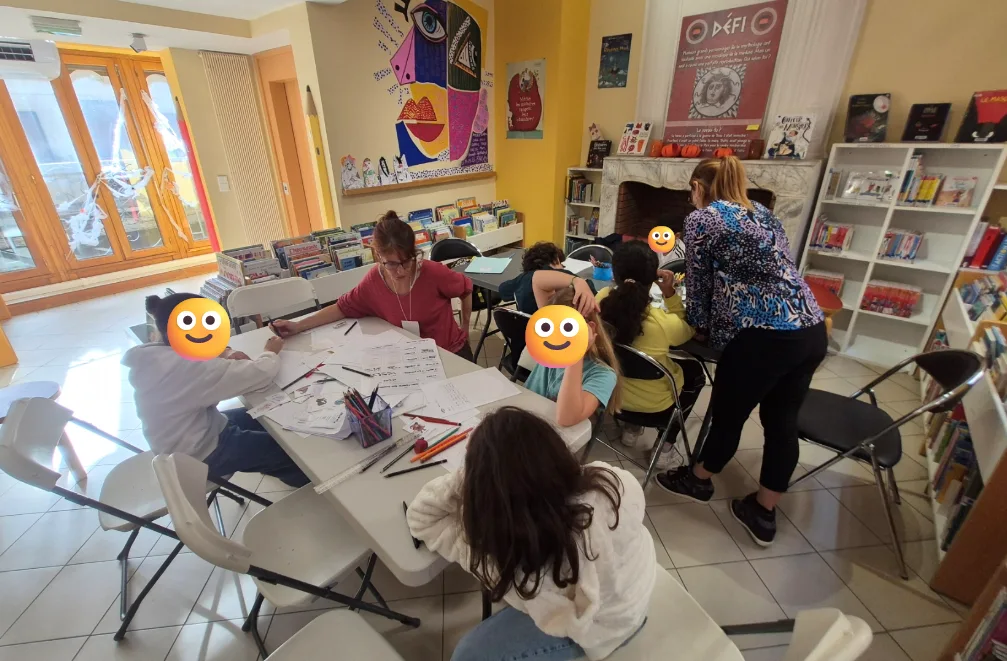 Enfants et adultes réunis autour des feuilles d’écriture pendant l’atelier collectif