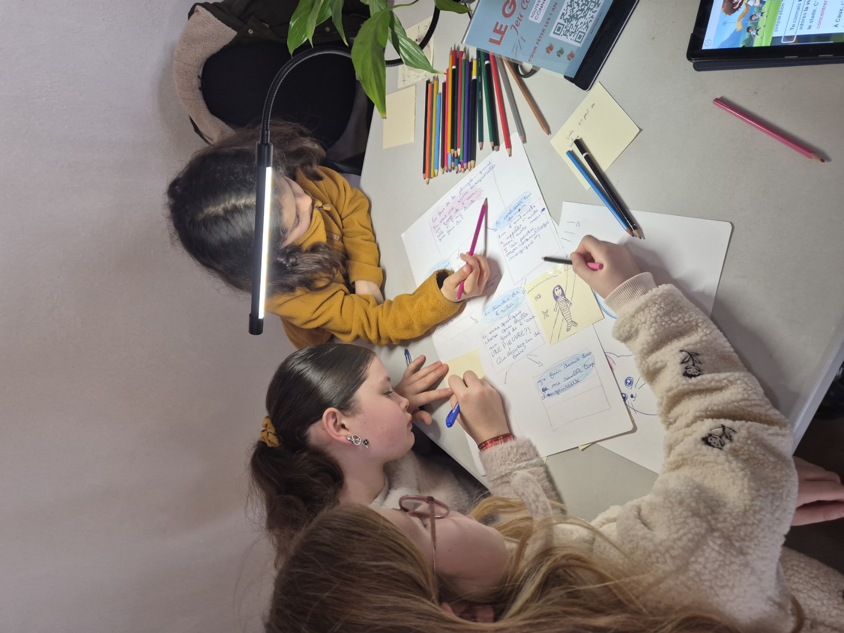 Enfants qui écrivent et illustrent une histoire interactive pendant un atelier en médiathèque